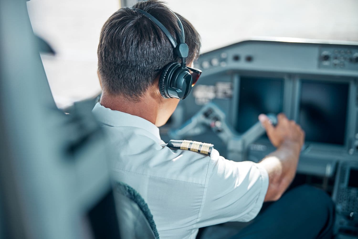 Pilot wearing a headset at the controls of an aircraft cockpit